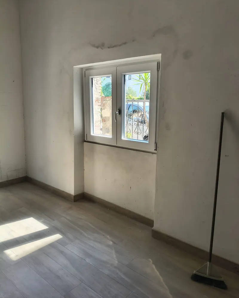 Finestra bianca a due ante in PVC in una stanza finita con pavimento in legno