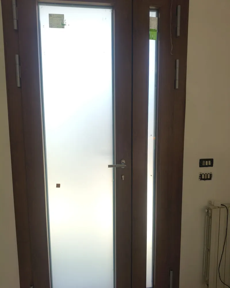 Porta d’ingresso effetto legno scuro con vetro satinato e fisso laterale
